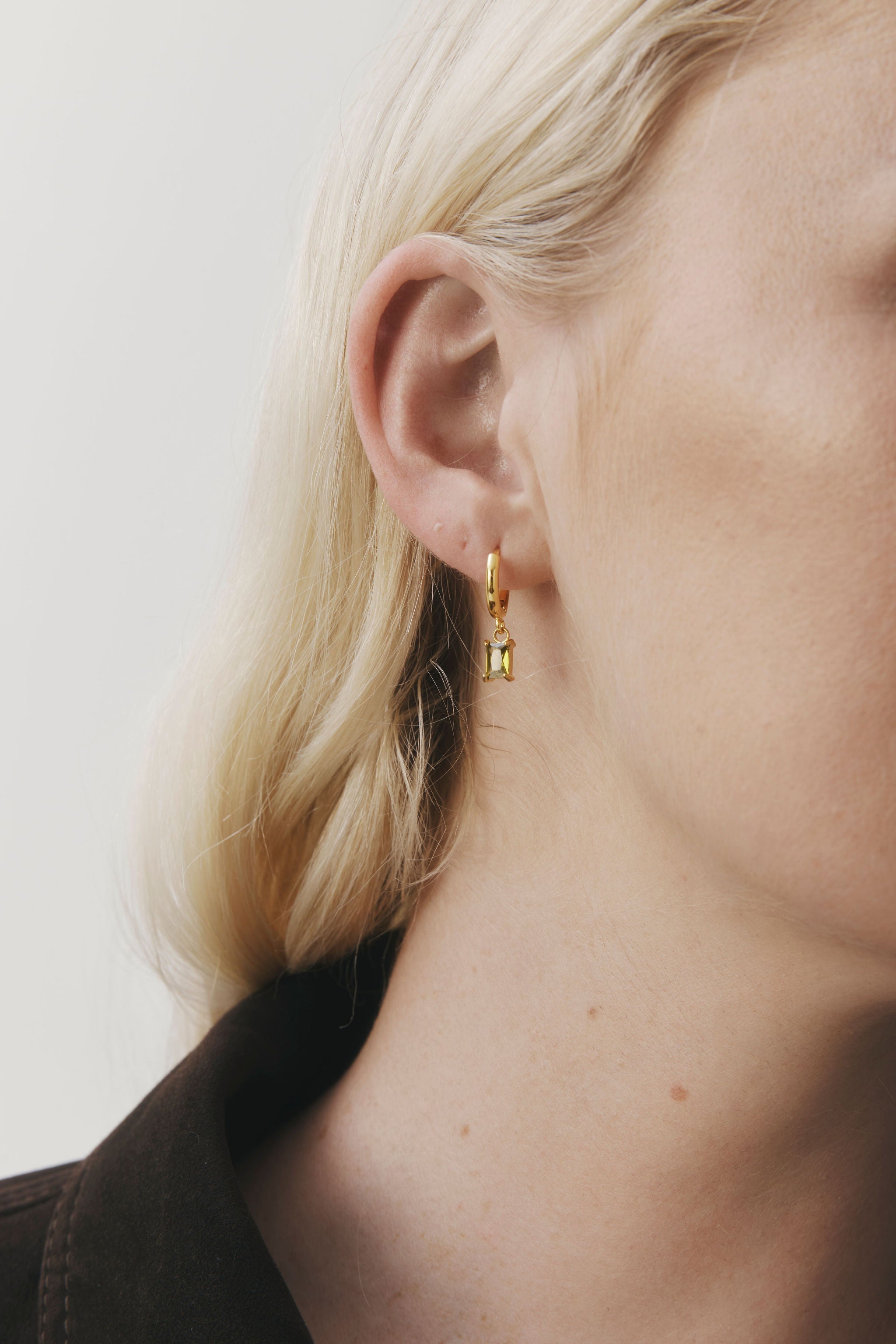 Arina Earrings by Castel & Co are gold-plated stainless steel hoop earrings featuring an olive green stone drop. Designed with a slim, elegant silhouette, they offer a lightweight feel (3g) and a Congo closure, measuring 2.2 x 0.4 cm. Crafted to catch the light with movement, they’re suitable for both everyday wear and evening styling. Hypoallergenic and waterproof.