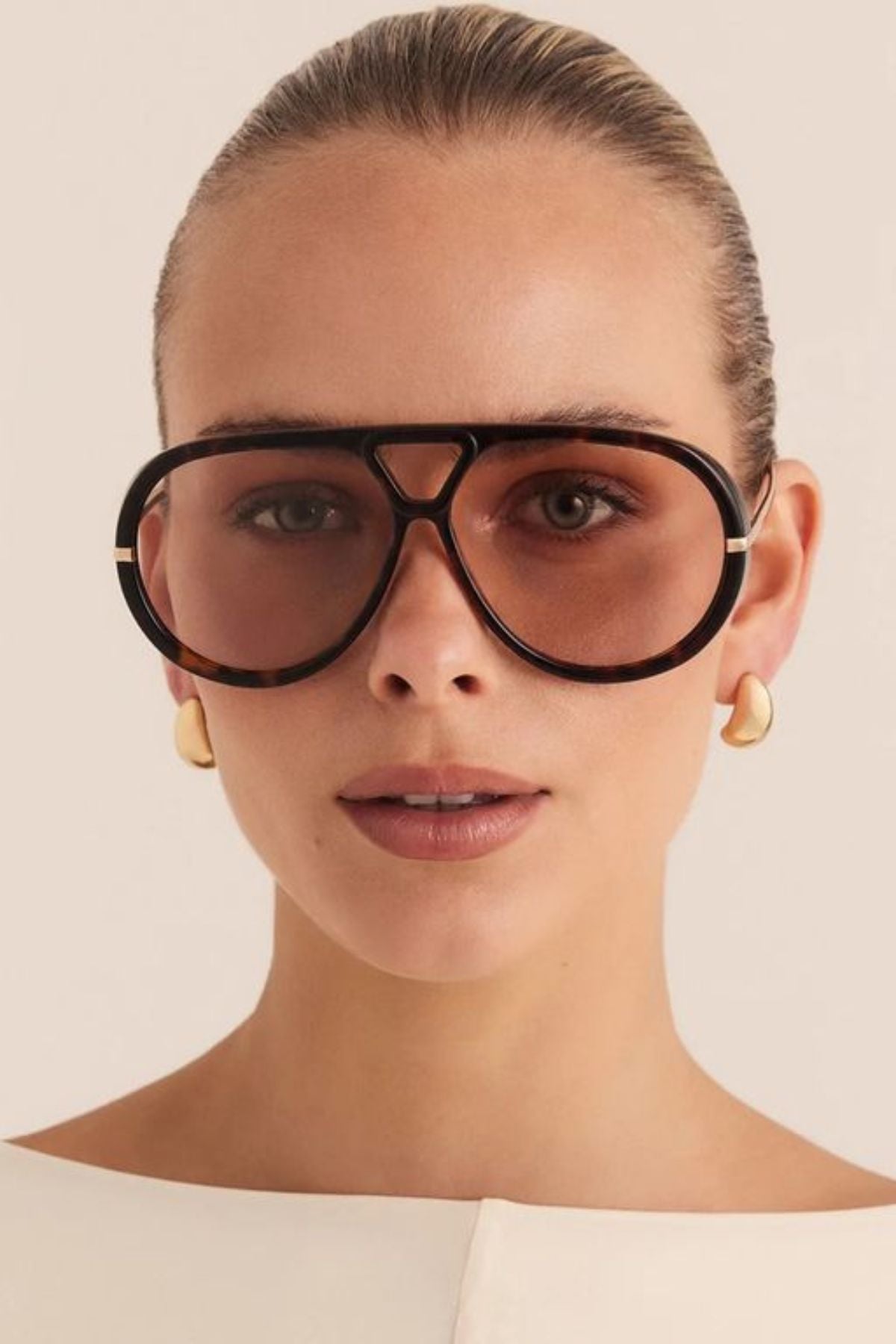 The Harley by BANBE is a bold aviator-style frame designed with a modern edge and refined everyday appeal.

Featuring light-tinted lenses, a distinctive double-bridge design, and slim gold-toned temples, this statement silhouette blends classic aviator influence with contemporary detailing.