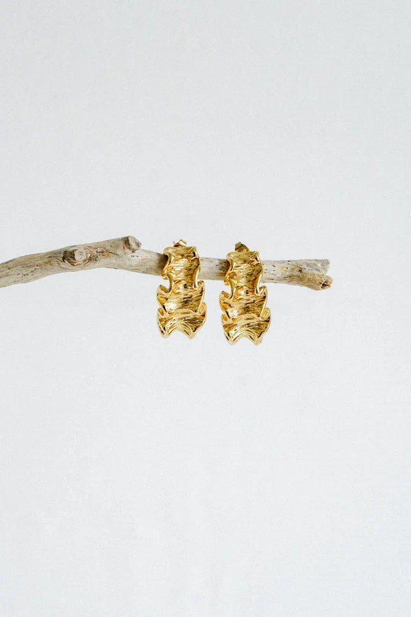 Textured, bold, and effortlessly chic—the Castel & Co Crinkle Earrings in Gold bring a sculptural edge to classic jewellery. Their organic, rippled design reflects light beautifully, creating a statement that feels both modern and timeless. Perfect for adding depth to minimal looks or enhancing an already bold ensemble, these earrings offer a sophisticated yet playful finish to any outfit.

Main material: gold plating, stainless steel
Closure type: stud
Earrings size: 3 x 1,5 cm
Waterproof/ hypoallergenic