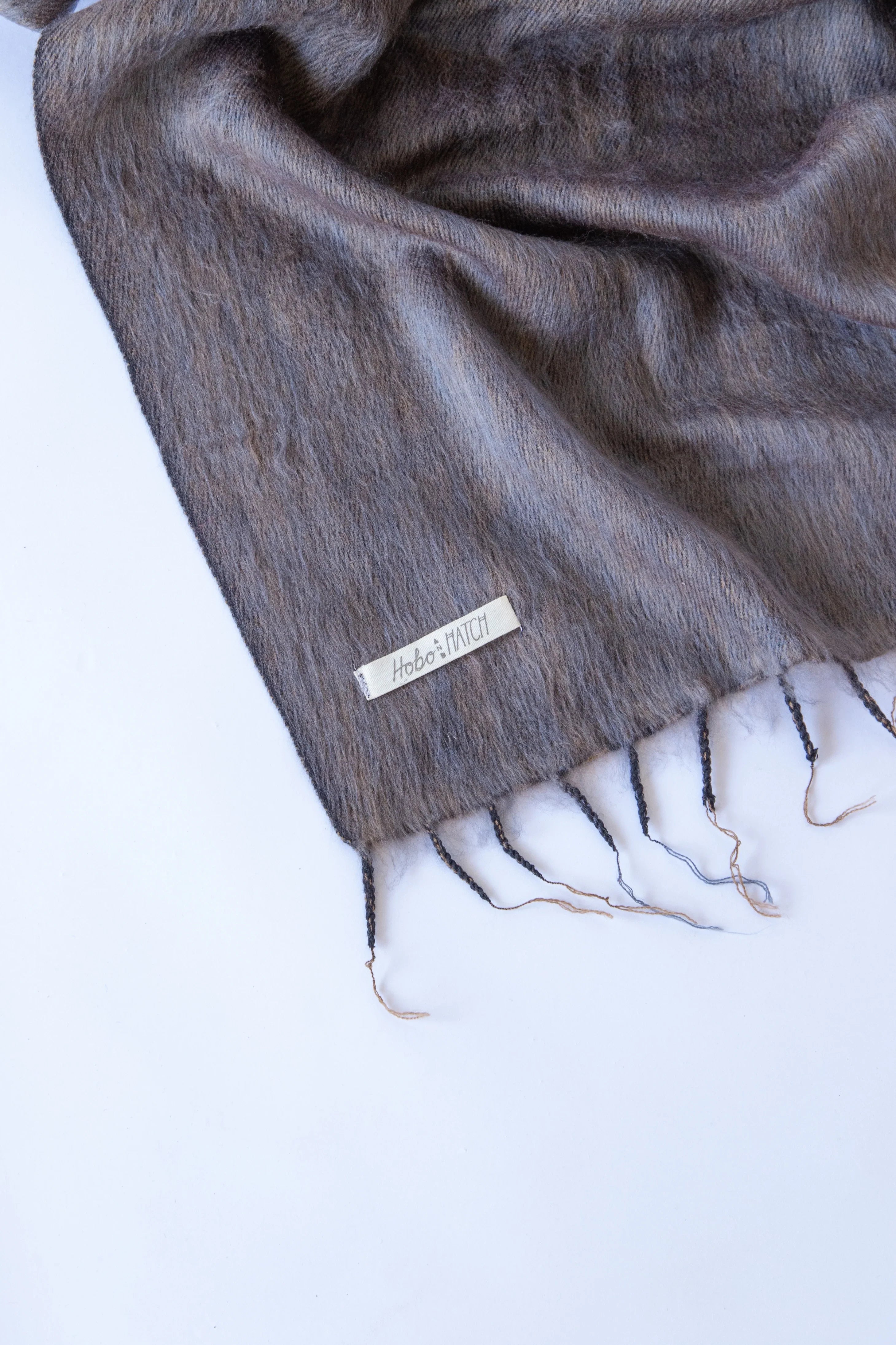Meet the layer you’ll reach for repeatedly. Worn as a shawl, wrap or scarf, this timeless piece moves effortlessly from slow mornings to cool evenings. Cosy yet refined, it’s made for early yoga flows, windswept beach sunsets, and everything in between.

Lightweight but warming, it’s the ultimate travel companion - wrapping you in comfort and that familiar, at-home feeling wherever you land.

Available in: Mulberry &amp; Hazelnut.

Details
• Approx. 76cm x 188cm
• Cool hand-wash, dry with care
• Handwoven i