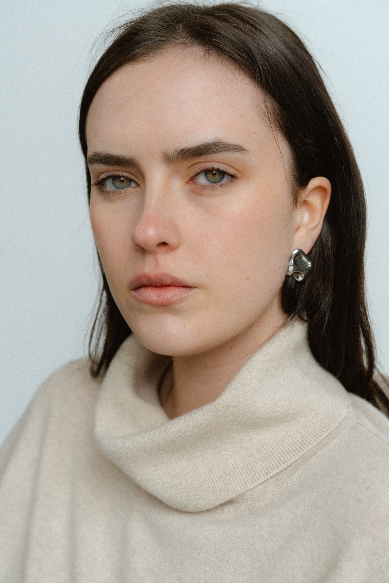 Molten Earrings by Castel and Co in polished silver, featuring sculptural, organic liquid-like curves that reflect light for a bold yet timeless statement. Stud closure with a 2 x 2 cm size, made from stainless steel, lightweight at 6g, waterproof and hypoallergenic.