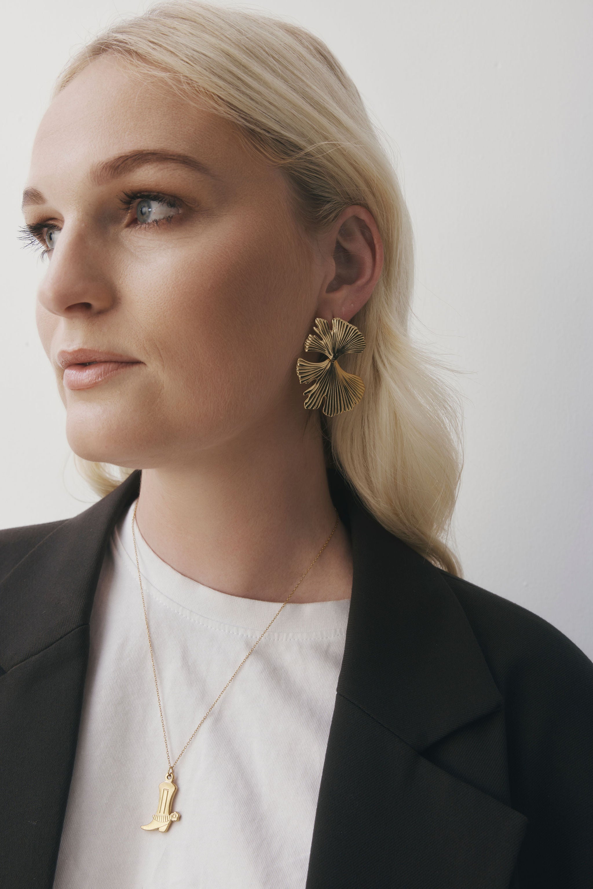 MUSE Earrings in warm gold with a sculptural, statement silhouette, designed to feel bold yet easy to wear. Stud closure with an oversized 8 x 8 x 2 cm form, crafted from stainless steel with gold plating. Waterproof, hypoallergenic, and lightweight for their size at 17g.