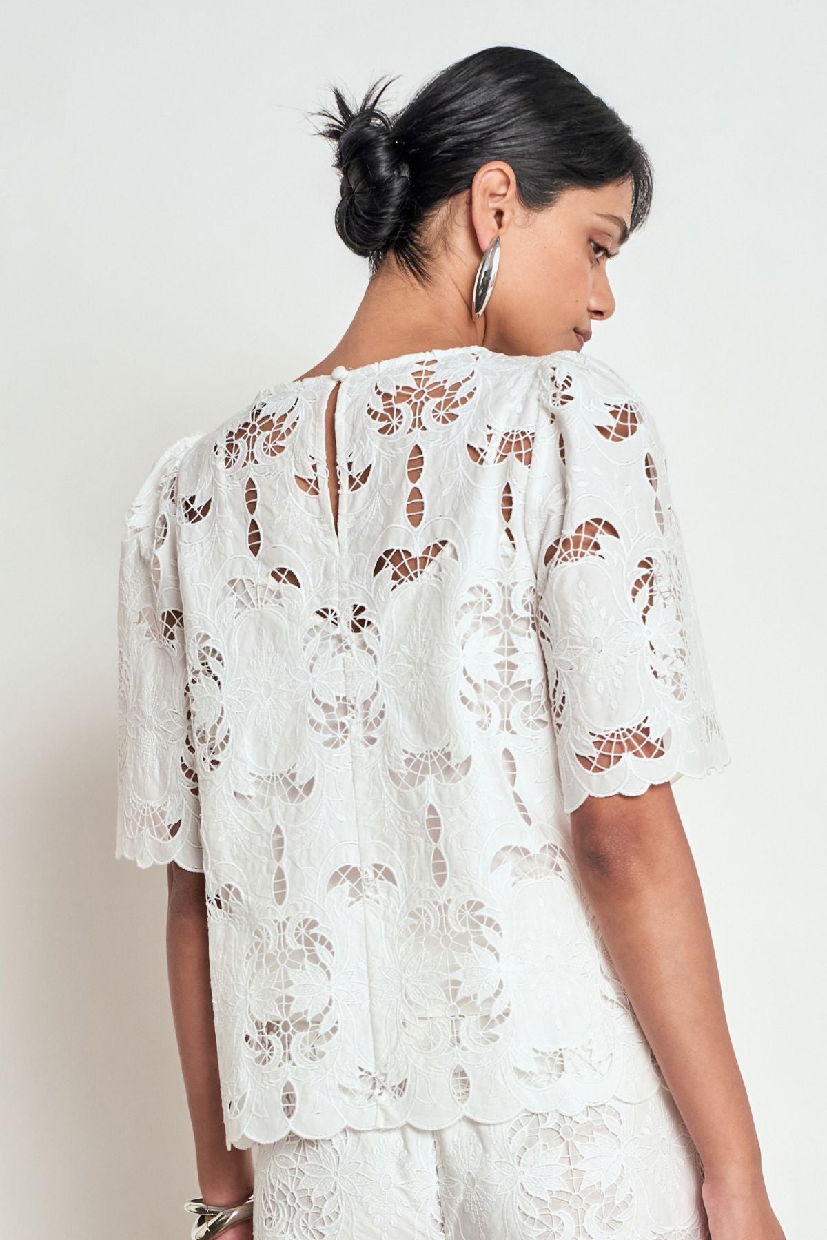Discover the Zoe Kratzmann Resolve Top in Alabaster. Crafted from intricate 100% cotton lace with gathered short sleeves, a classic round neckline and cami included.