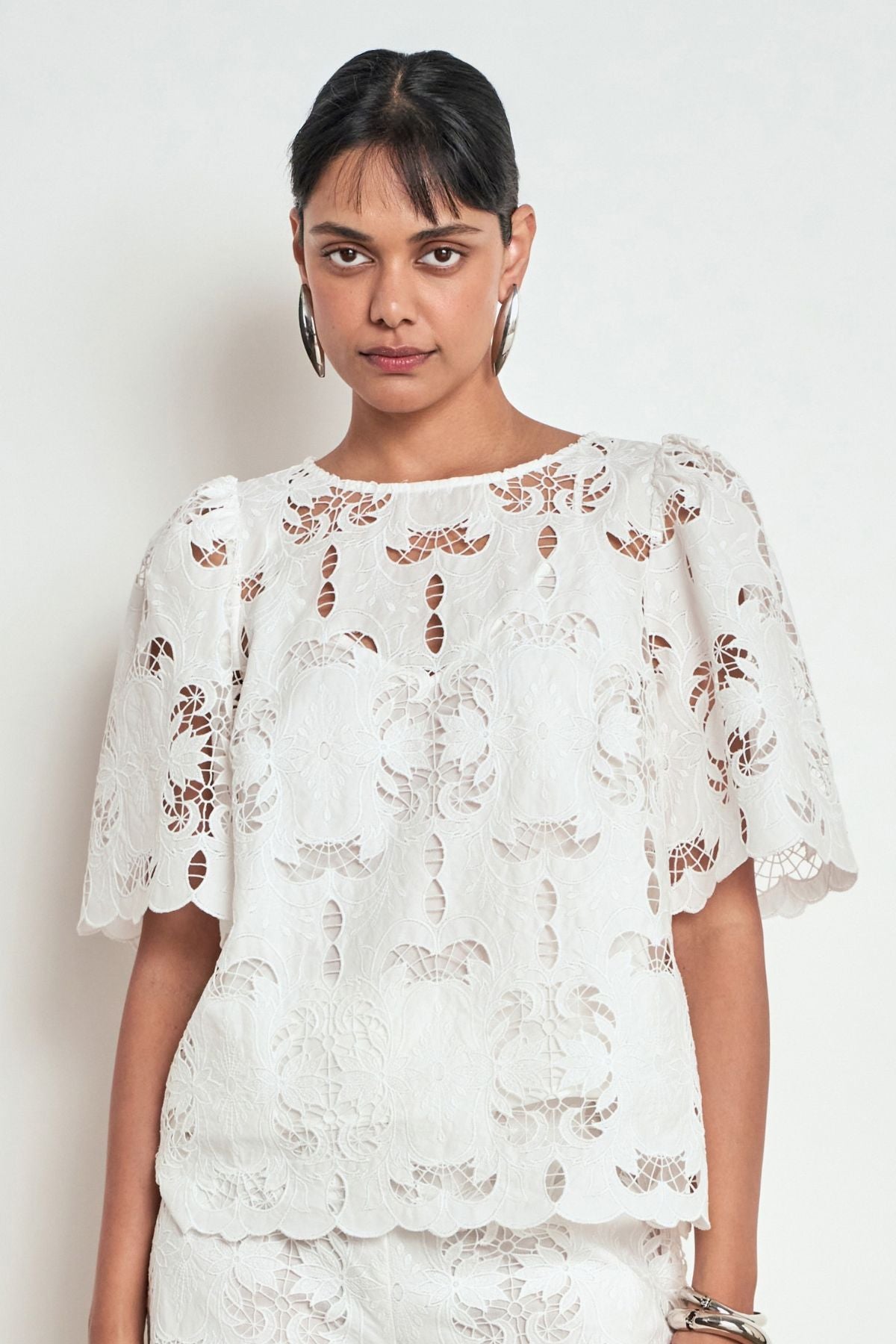 Discover the Zoe Kratzmann Resolve Top in Alabaster. Crafted from intricate 100% cotton lace with gathered short sleeves, a classic round neckline and cami included.