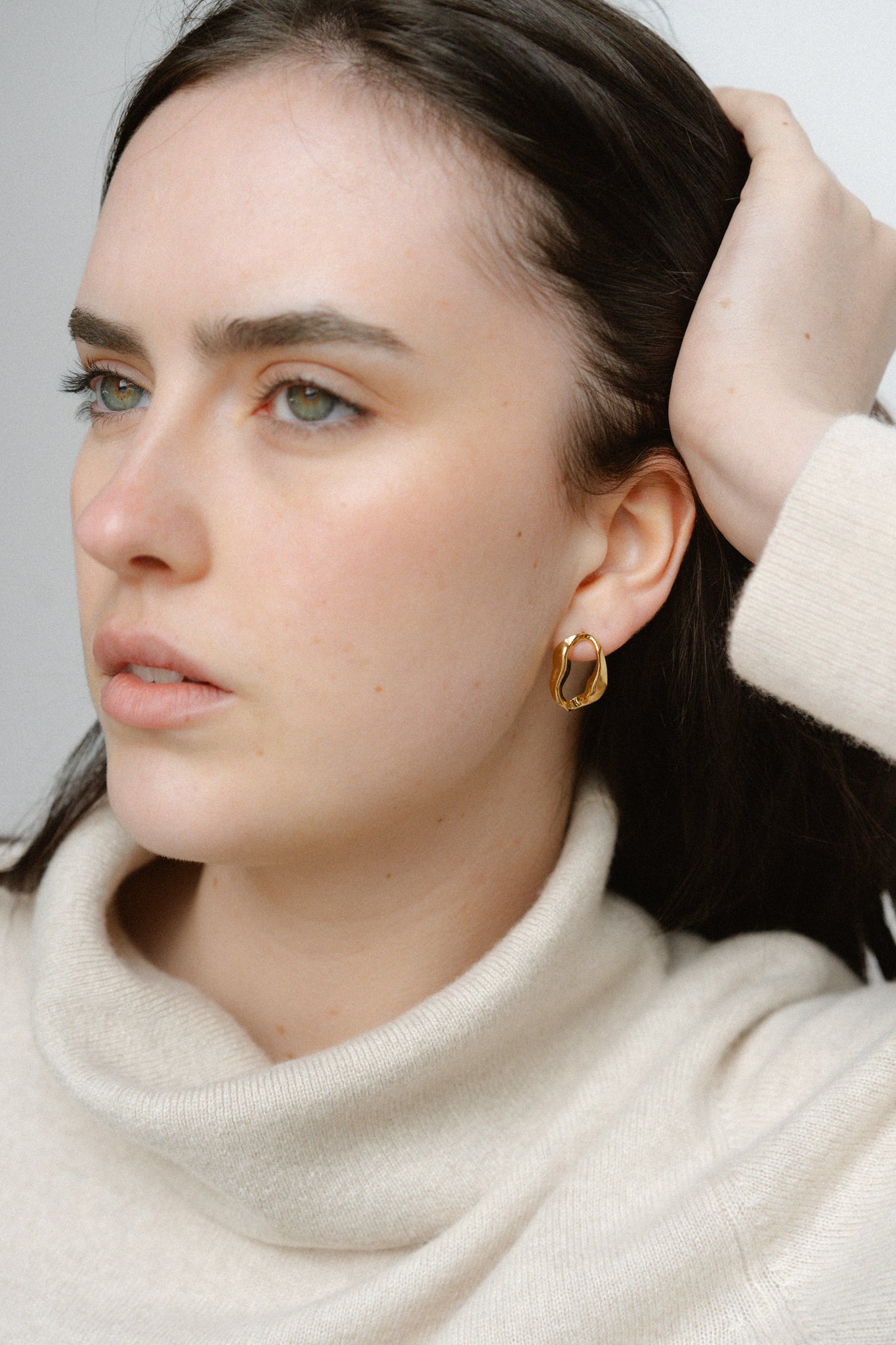 Aurora Earrings by Castel & Co are gold-plated stainless steel sculptural hoop earrings featuring a fluid, organic silhouette. Designed with a modern, artistic shape that balances statement appeal with everyday wearability, they are lightweight (3g) with a stud closure and measure 2.1 x 1.4 cm. Hypoallergenic and waterproof.