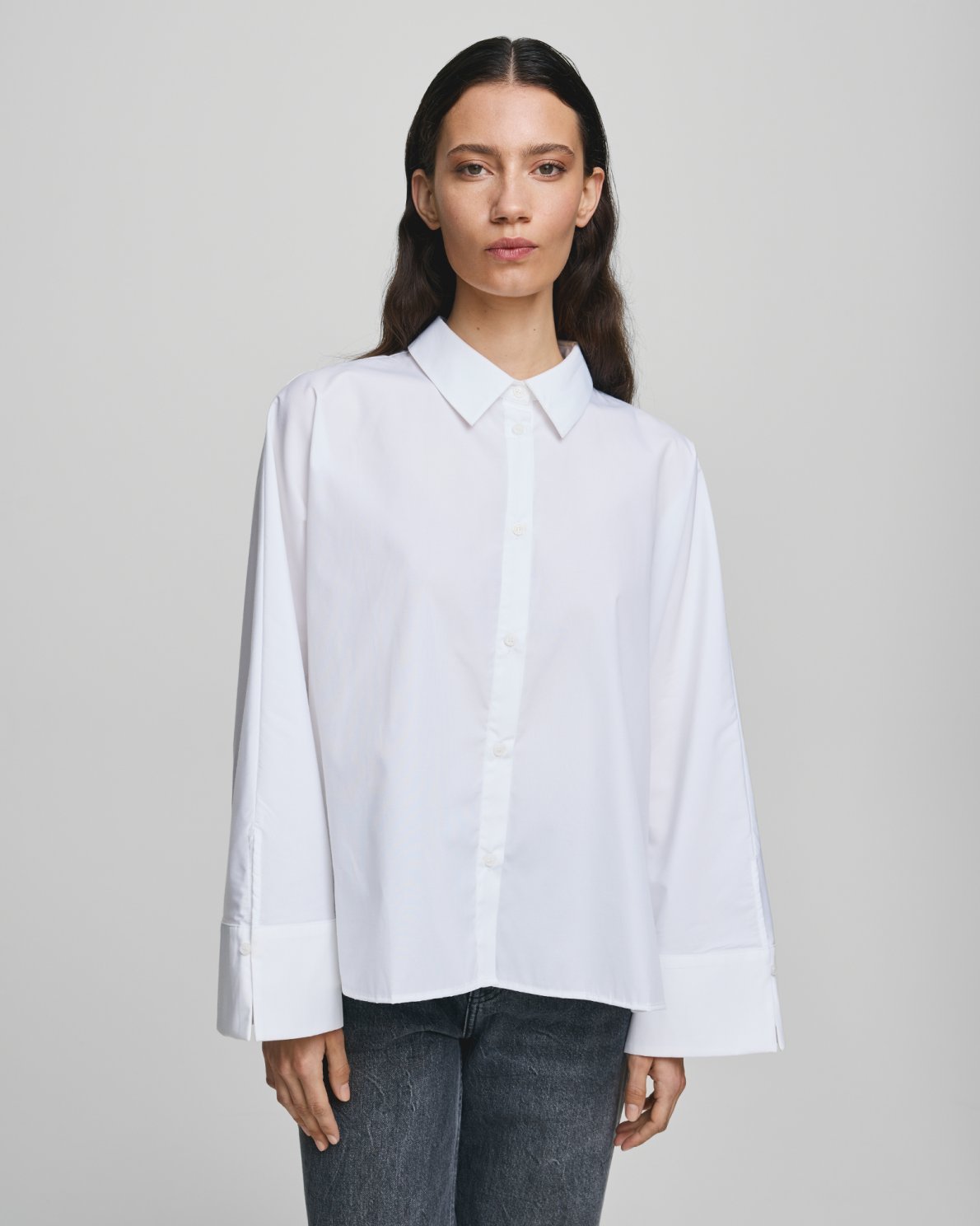 MSCH Copenhagen NATALIA ZENIKA Boxy Shirt in black with a clean structured silhouette, classic collar and full front button closure. Features long sleeves with wide cuffs and an adjustable back button detail to define the waist or wear loose. Crafted from a smooth recycled polyester and cotton blend.